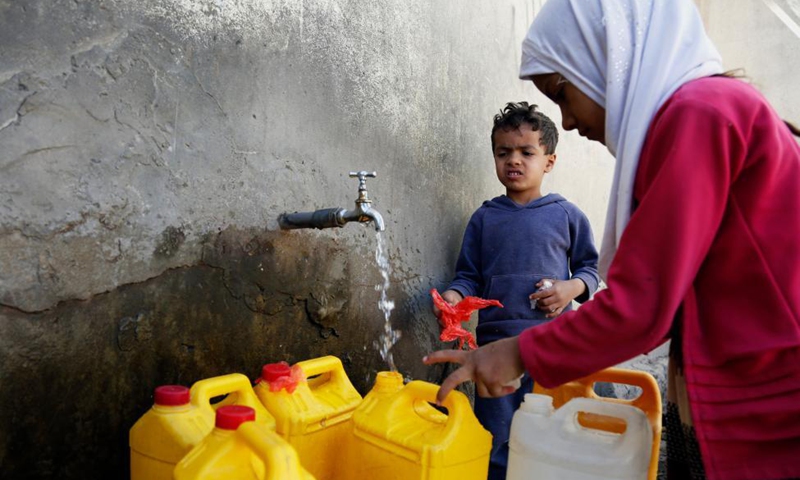 Yemeni children fill plastic containers with water at charity water tap  site in Sanaa - Global Times